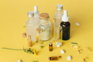 Frascos de aceites esenciales, hierbas y una flor amarilla destacando la aromaterapia. Descubre las 5 medicinas alternativas para una salud integral: acupuntura, aromaterapia, reiki, homeopatía y yoga.
