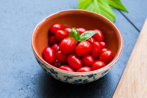 Un cuenco rebosante de vibrantes tomates cherry, una explosión de color y antioxidantes. ¡Disfruta de la frescura y los beneficios saludables de la dieta mediterránea en cada bocado!
