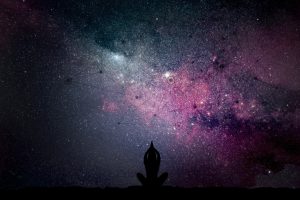 Ilustración del universo con figuras geométricas y una silueta de persona meditando con las manos juntas sobre la cabeza, simbolizando la conexión con la Conciencia Universal y la armonía cósmica.