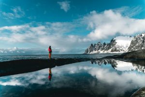 Persona disfrutando de la vista de un lago y montañas, conectando con la naturaleza.