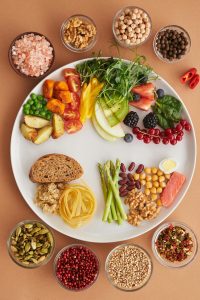 Plato equilibrado con variedad de alimentos: frutas, verduras, granos enteros y proteínas magras.