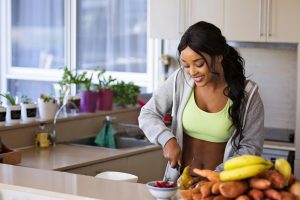 Joven sonriente preparando frutas frescas como parte de un estilo de vida saludable y equilibrado. Imagen de hábitos alimenticios saludables y bienestar físico.