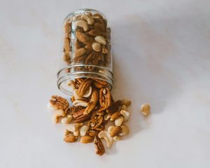Frutos secos, como cajus y nueces, cayendo de un frasco. Una fuente rica en vitamina E.