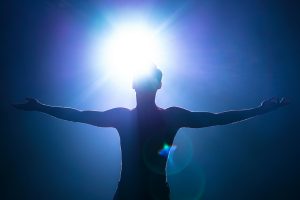 Hombre manifestando plenitud espiritual bajo el sol brillante.