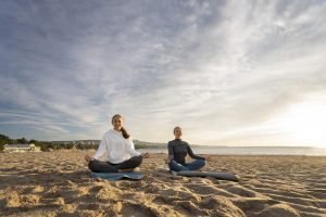 Personas meditando al aire libre durante una puesta de sol.