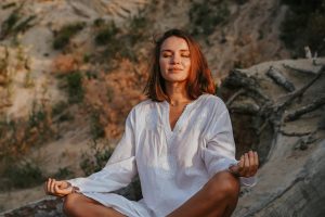 Mujer meditando en la naturaleza para encontrar paz interior y calmar la mente.