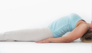 Mujer ejecutando la Postura del Pez para estirar la parte baja de la espalda y abrir el pecho.