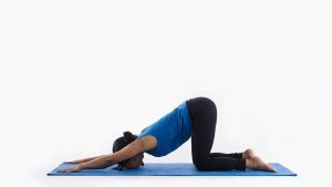  Mujer practicando la Postura del Cachorro en una esterilla de yoga.