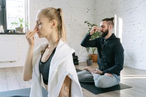  Dos personas practicando la técnica de pranayama Nadi Shodhana (respiración alterna), una forma efectiva de equilibrar la energía y reducir el estrés.