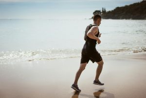 hombre corre en la orilla del mar. Disfruta de la combinación perfecta de nutrición y deporte para una vida plena y activa. 