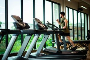 Persona trotando en una máquina de correr en un gimnasio: Mejora tu salud y bienestar con la actividad física en la vida diaria.