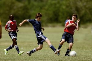 Adolescentes disfrutando de un partido de fútbol para mantenerse activos y saludables.