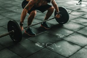 Hombre levantando peso con barra en el gimnasio.