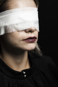 Imagen de una mujer con vendas en los ojos, simbolizando el despertar espiritual y el cambio de percepción hacia la Conciencia Universal.