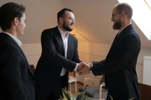 Dos hombres se estrechan la mano en señal de acuerdo, mientras sonríen con confianza. Una imagen de comunicación clara y efectiva para alcanzar objetivos comunes.
