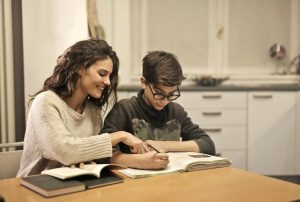 Hermana mayor ayudando a su hermano menor. Empatía a través de la educación y el apoyo emocional.
