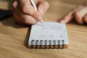 Persona escribiendo en una libreta, practicando habilidades de gestión del tiempo y desarrollo personal.