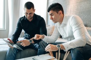 Dos empresarios revisan datos importantes en una tableta digital mientras discuten en un entorno profesional.