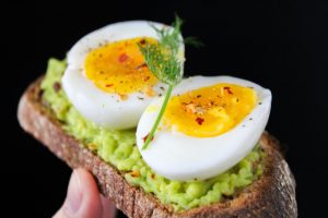 Huevo en rodajas sobre ensalada verde con pan tostado, una combinación deliciosa y nutritiva para una comida equilibrada.