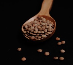 Lentejas en un cucharón de madera, fuente de hierro para una dieta nutritiva en la adolescencia.