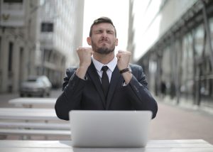Empresario celebrando un logro con los puños cerrados y los ojos cerrados de satisfacción.