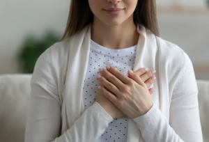 Mujer con las manos en el corazón, expresando amor y conexión con su chakra corazón.