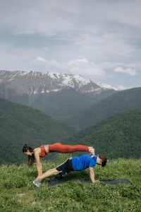 Pareja practicando la postura de la plancha doble en yoga en pareja, fortaleciendo los músculos y la conexión física.
