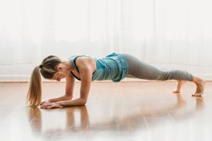 Mujer realizando ejercicio de plancha en casa para fortalecer su cuerpo y mejorar su salud. Integra la actividad física en tu rutina diaria para lograr un estilo de vida más saludable.