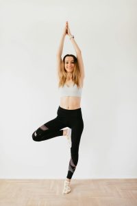 Mujer practicando la postura del árbol (Vrksasana) para equilibrar el chakra raíz