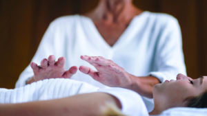 Terapeuta practicando terapia alternativa de Reiki sobre el pecho de una mujer.